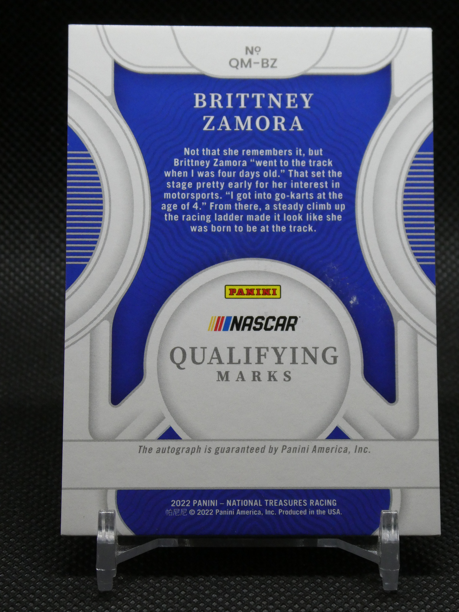 Panini NASCAR qualifying marks card for Brittany Zamora with a blue and white circular design in the background.