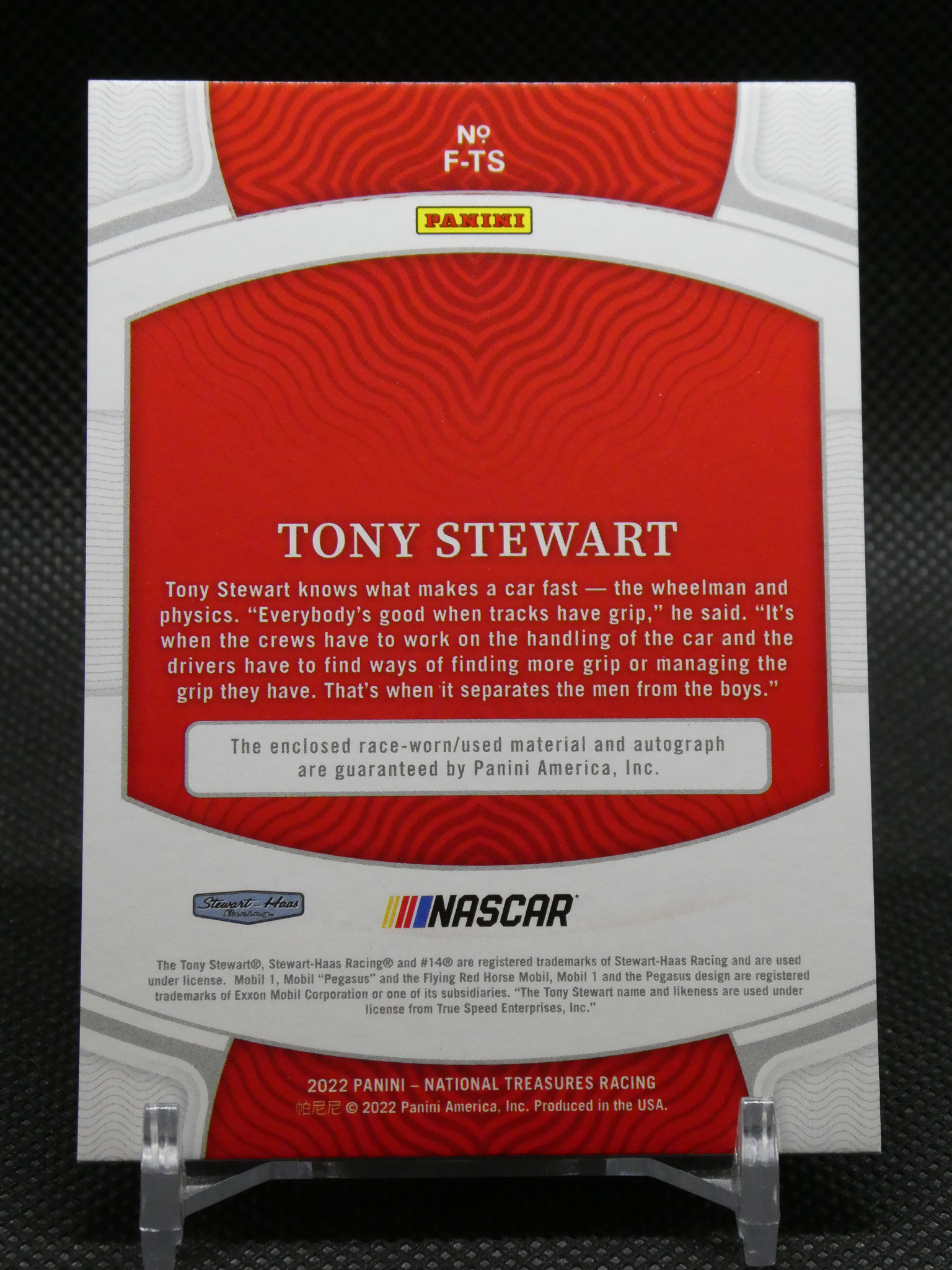 Panini NASCAR card back featuring Tony Stewart bio on a red patterned panel with logos in white and gray borders.