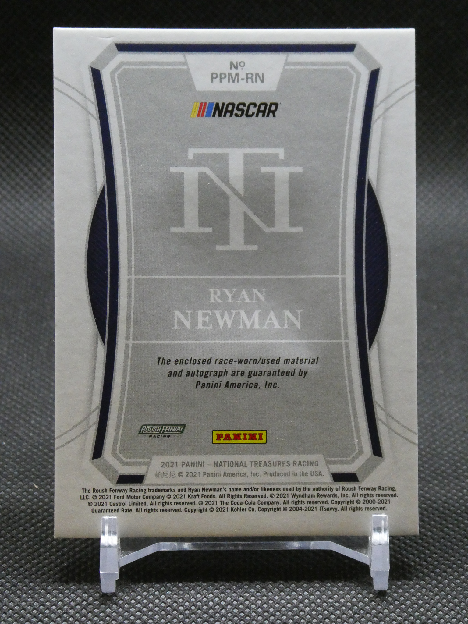 Panini NASCAR trading card for Ryan Newman in a display stand, featuring large NT initials and NASCAR logo.