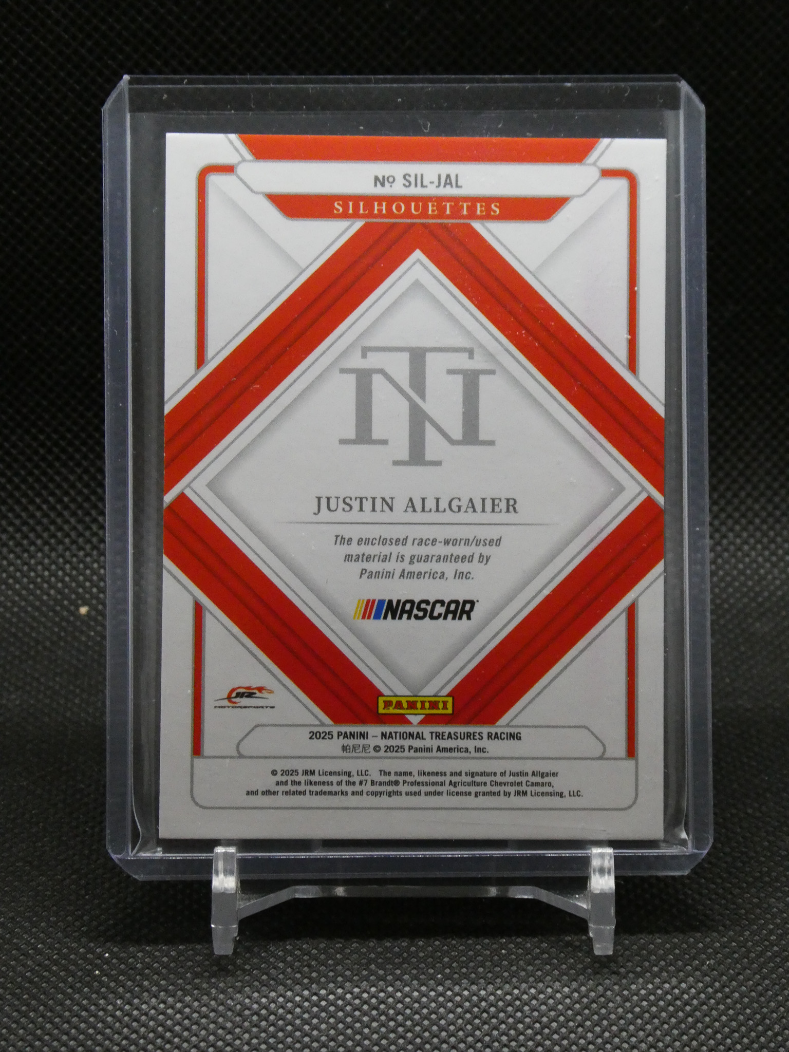 Trading card encased in plastic sleeve featuring red diagonal cross design and 'NT' initials with 'Justin Allgaier' and Panini logo, NASCAR-branded card.