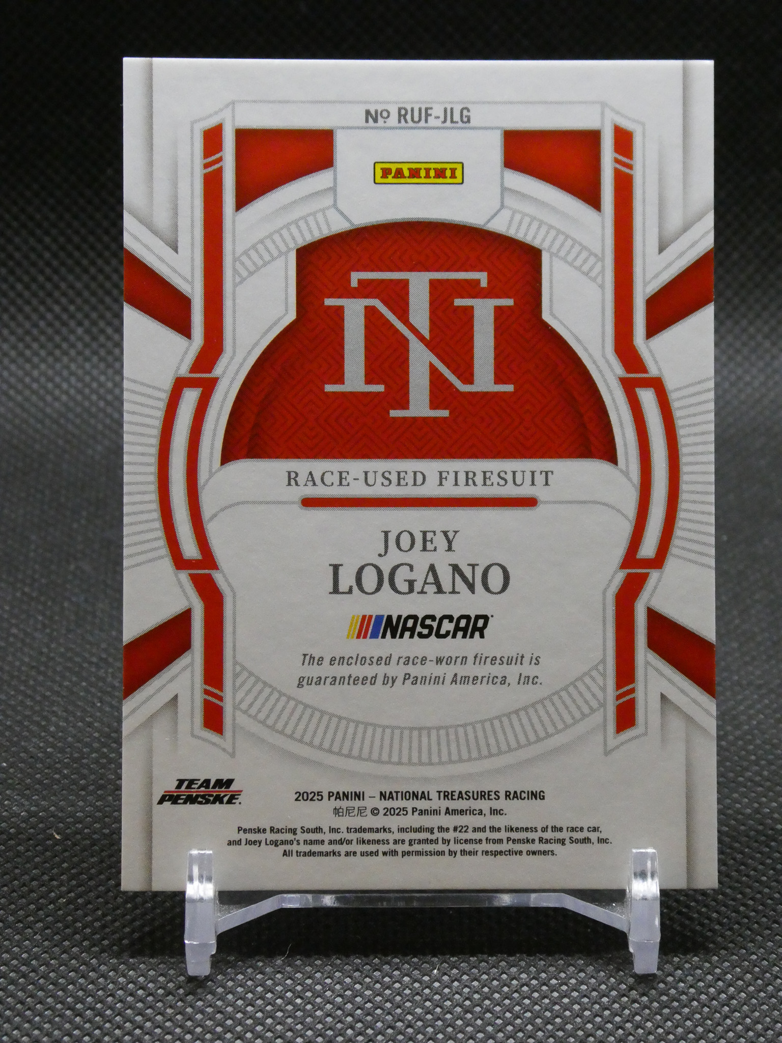 Panini NASCAR card featuring Joey Logano with a large red TNT emblem and 'Race-Used Firesuit' text, mounted on a display stand.