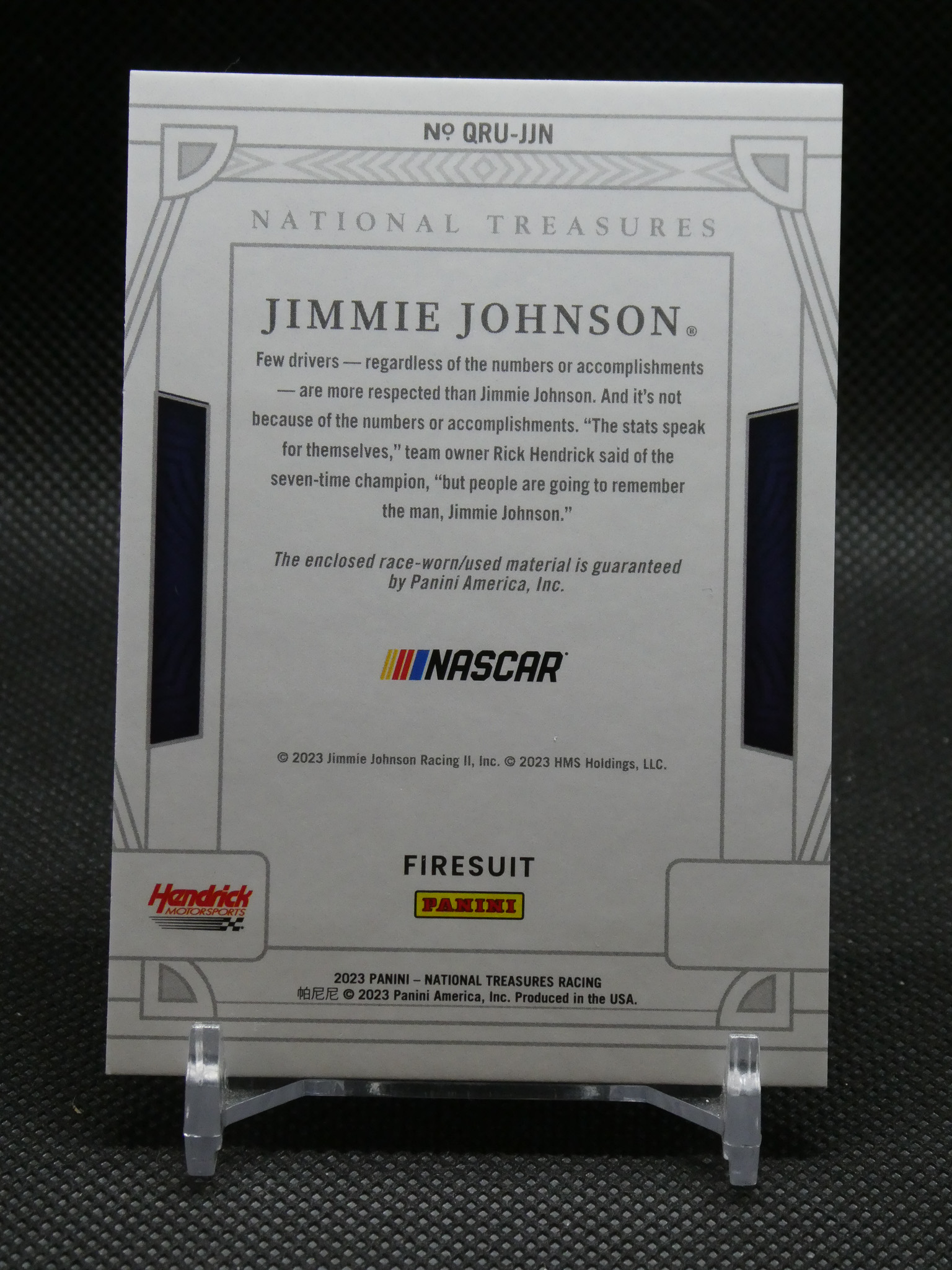Back of a Jimmie Johnson NASCAR trading card with a biography paragraph and NASCAR/Panini logos displayed on a stand at the bottom left and center.
