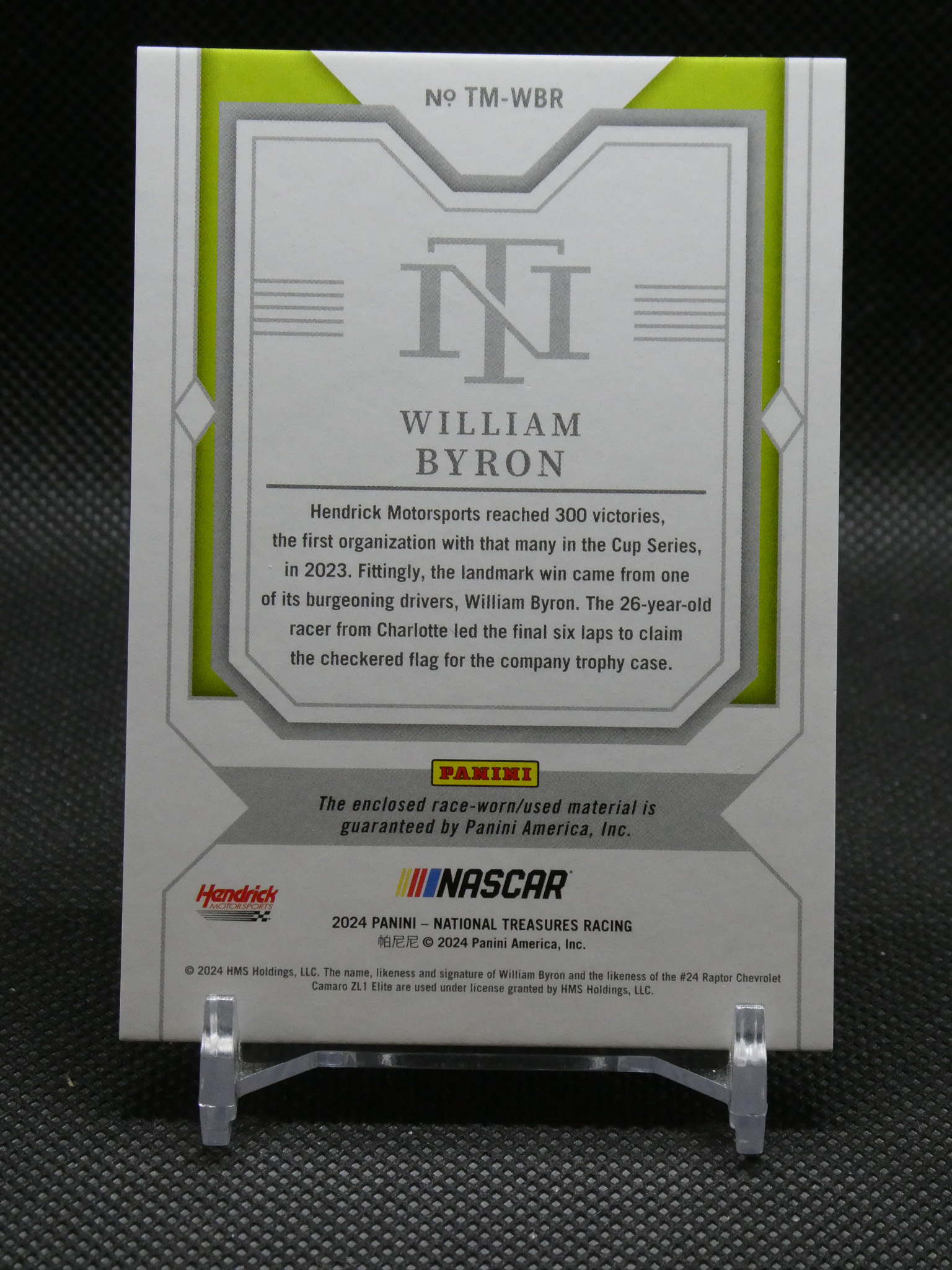 Panini NASCAR card honoring William Byron with a gray geometric frame and lime accents, including victory notes and logos on a display stand.