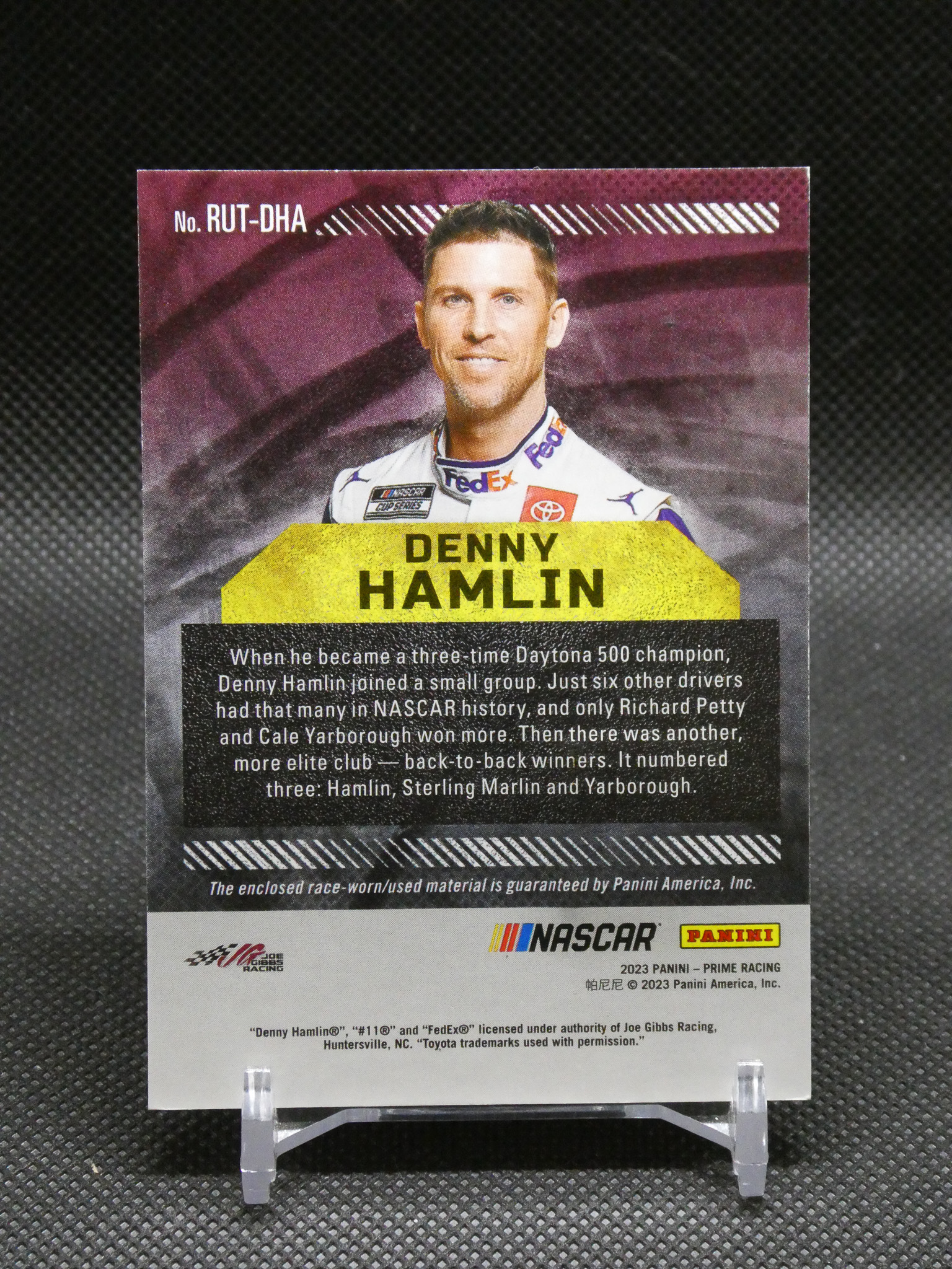 Denny Hamlin trading card portrait with a yellow name banner, bio text below, and sponsor logos at the bottom.