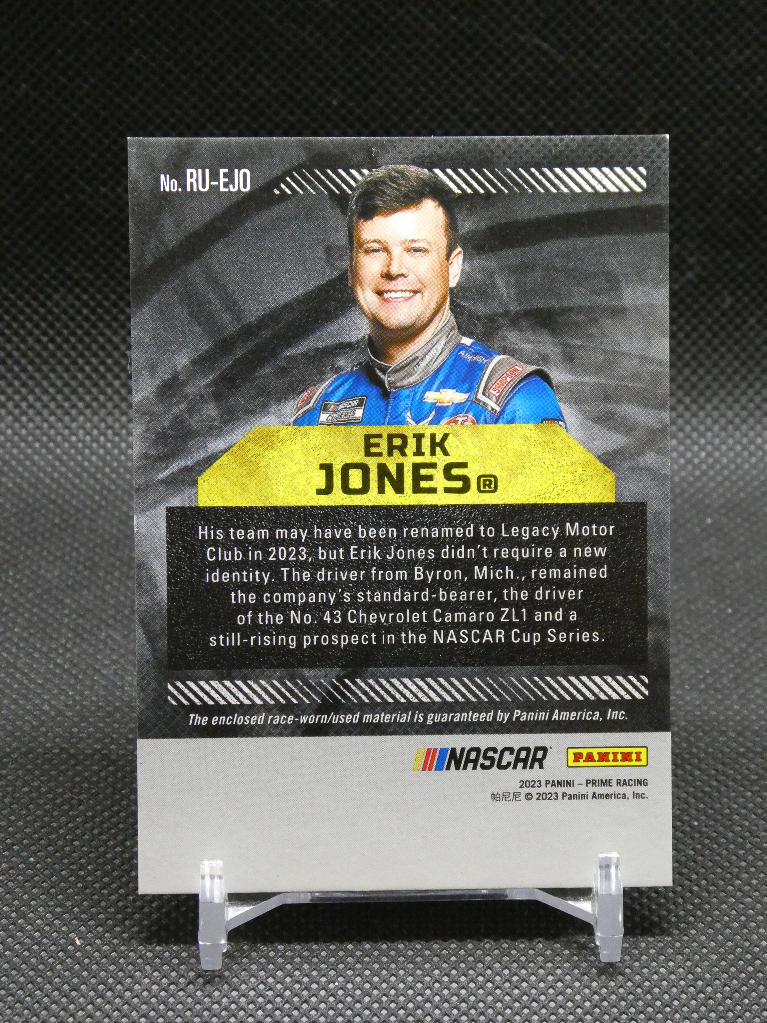 NASCAR trading card showing driver Erik Jones in a blue suit with a yellow name banner reading ‘ERIK JONES’ and a bio block below.