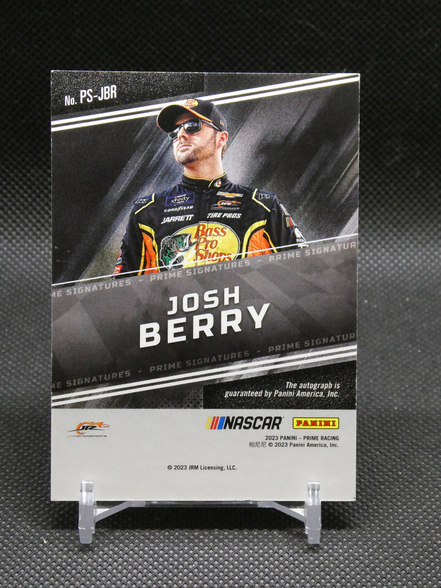 Card featuring NASCAR driver Josh Berry in a black and yellow racing suit with Bass Pro Shops logo, standing under a angled design; text reads 'JOSH BERRY' and 'No. PS-JBR' with Panini/NASCAR branding at the bottom for Prime Signatures edition.