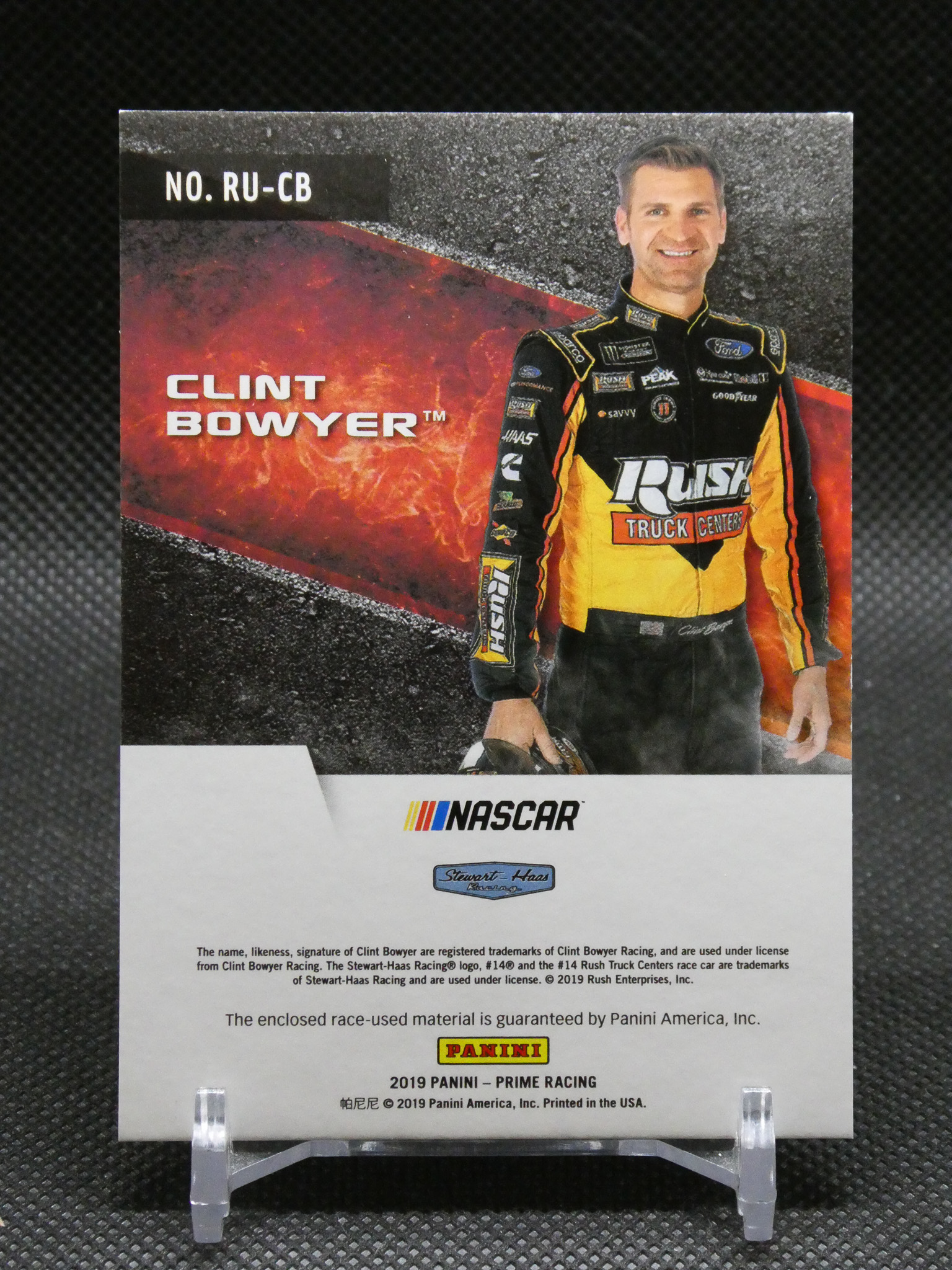 Trading card featuring NASCAR driver Clint Bowyer in a yellow-black racing suit against a fiery background, with NASCAR and Panini logos.
