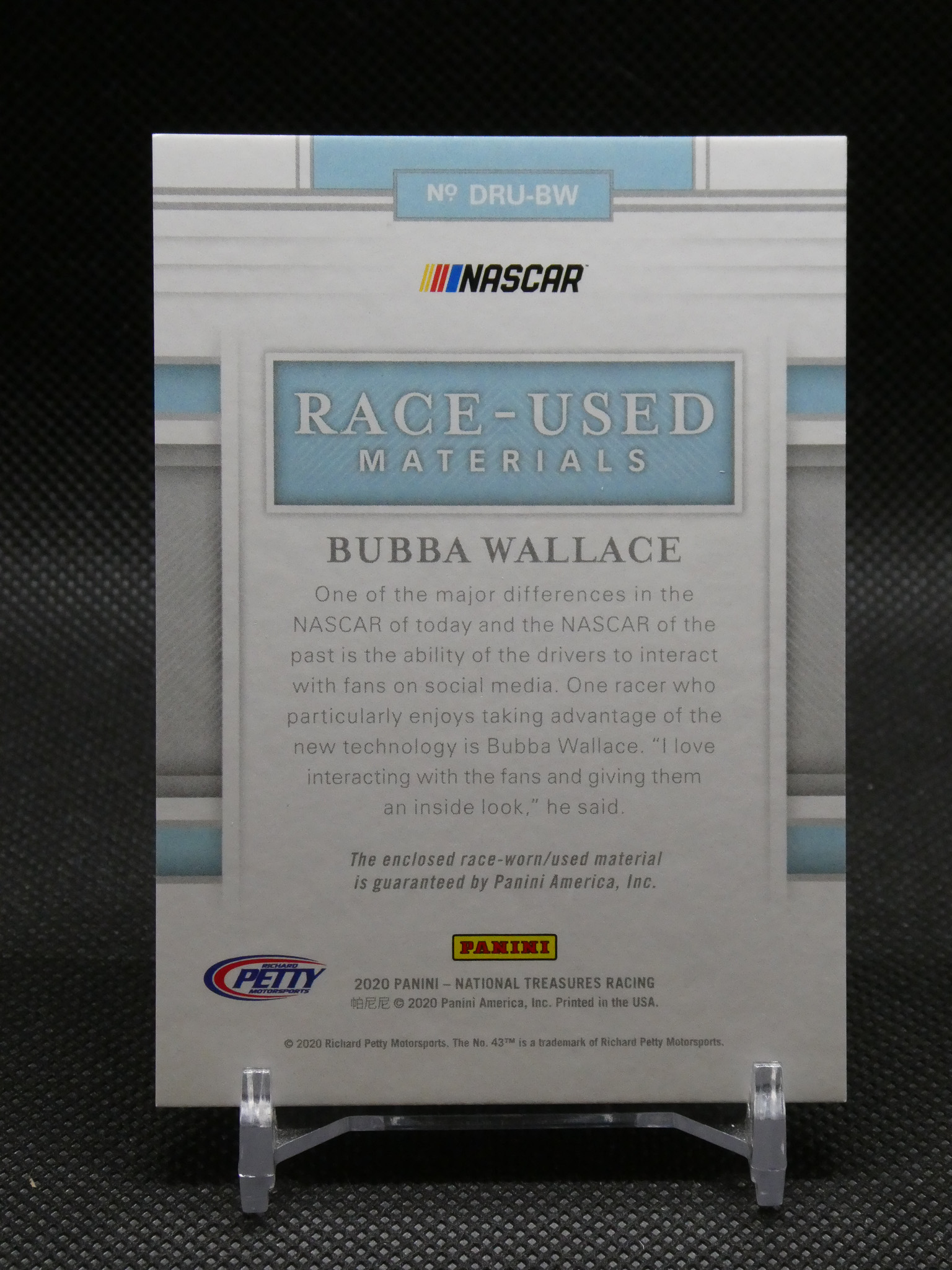 Panini NASCAR Race-Used Materials card featuring Bubba Wallace on a display stand, with logo and descriptive text on the card.