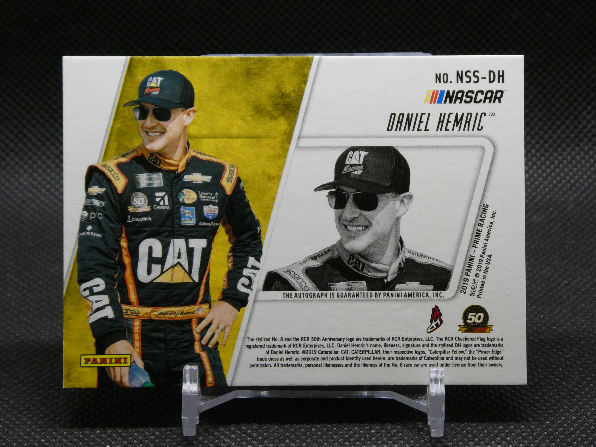 Panini NASCAR trading card of Daniel Hemric, showing a color photo of Hemric in a CAT racing suit on the left and a grayscale inset portrait on the right.