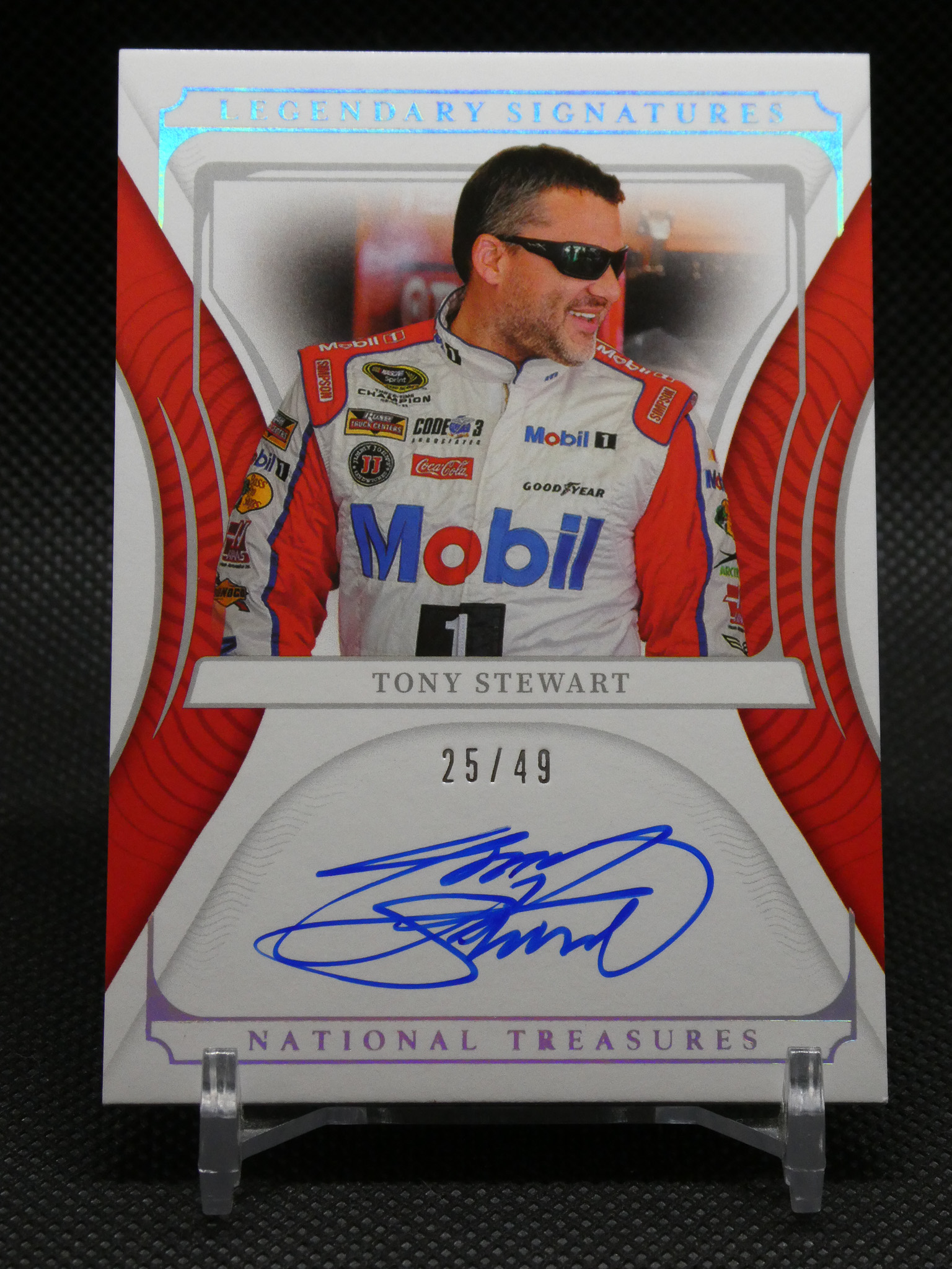 Autographed Tony Stewart trading card from National Treasures, numbered 25/49, featuring him in a red-and-white racing suit.