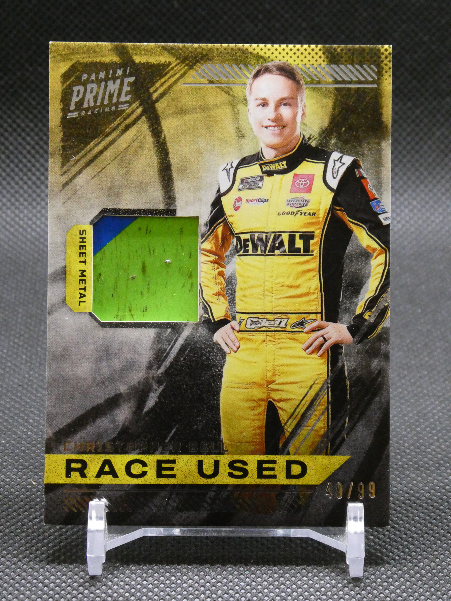 Panini Prime Racing card featuring a smiling driver in a yellow DeWalt racing suit with a 'Race Used' banner at the bottom.
