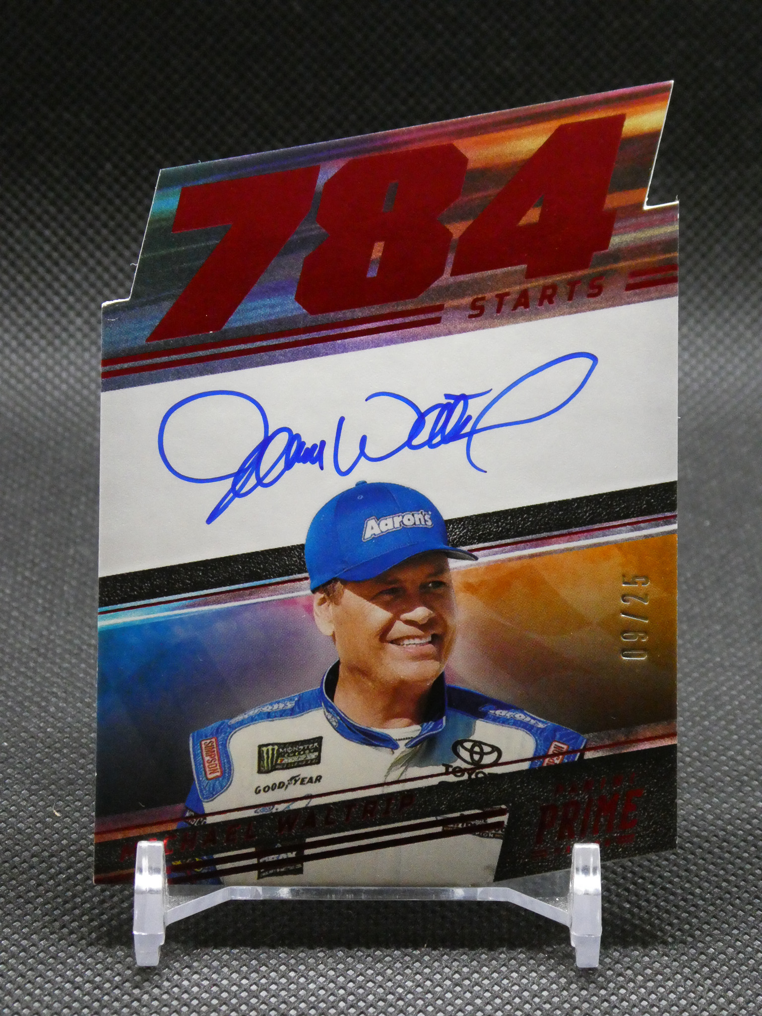 Promotional poster featuring a smiling racecar driver in a blue cap with an Aaron's logo, autograph in blue marker, and bold red lettering at the top.