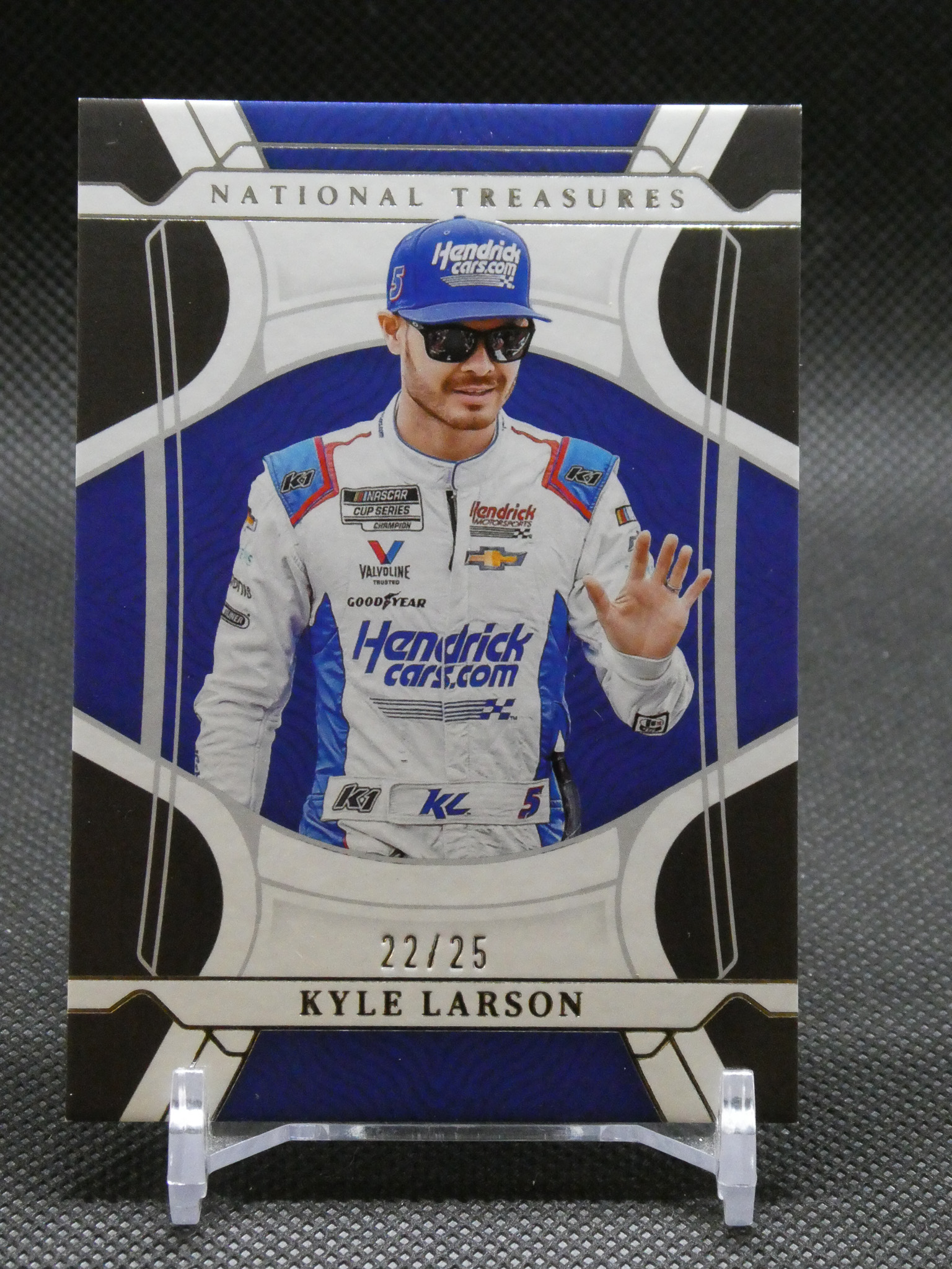 Limited-edition Kyle Larson trading card (22/25) on a display stand, featuring Larson in a Hendrick Motorsports suit.