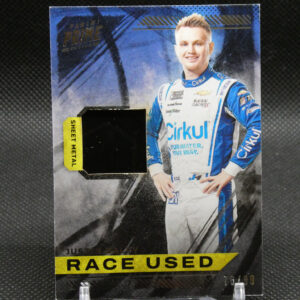 Promotional card showing a race car driver in a blue and white racing suit, with a yellow 'RACE USED' banner along the bottom.