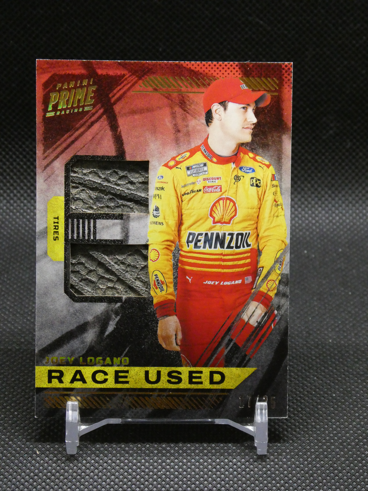 Trading card featuring NASCAR driver Joey Logano in a yellow Pennzoil racing suit with 'RACE USED' label at bottom.