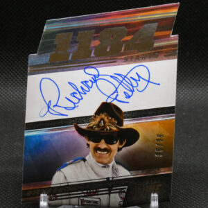 Autographed poster of a smiling race driver in a white suit wearing a cowboy hat and sunglasses, with a blue signature across the image, displayed on a clear stand.