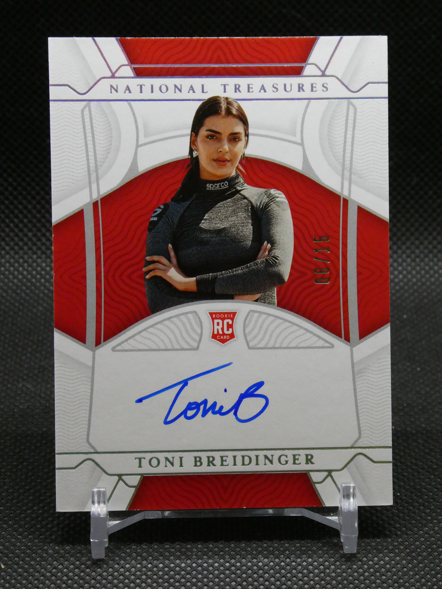 Front of a National Treasures rookie card featuring Toni Breidinger in a dark racing suit, with a blue autograph across the lower area.
