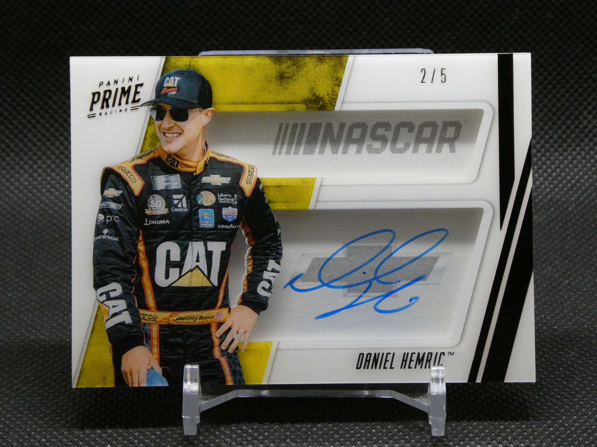Trading card featuring racecar driver Daniel Hemric, with a blue autograph and 2/5 print count visible at top right.