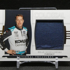 Brad Keselowski in a white racing suit stands beside a dark blue fabric swatch on a display card labeled Colossal and National Treasures