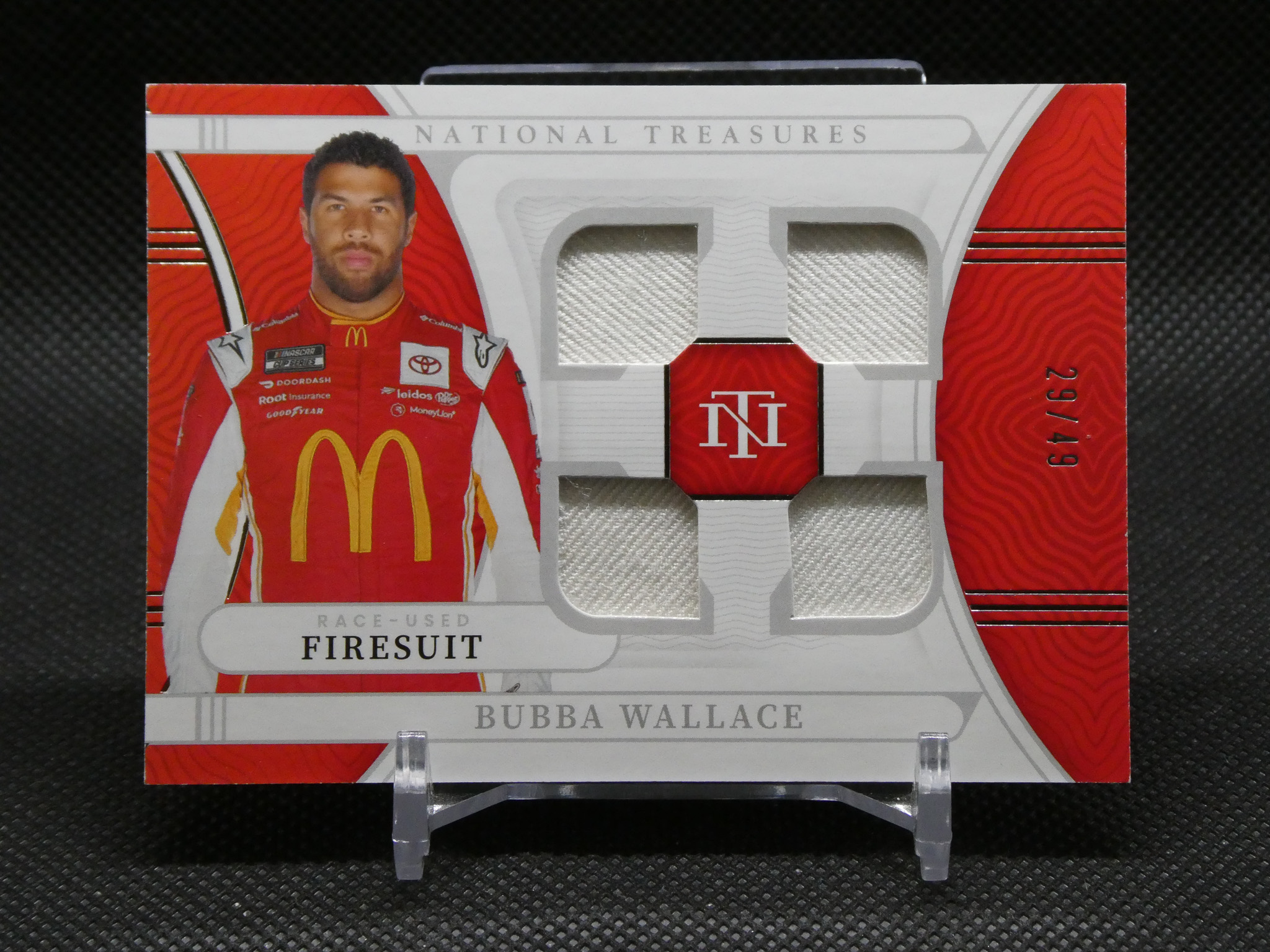 Red NASCAR firesuit display box featuring a driver in a red uniform with McDonald's logo, visible fabric swatches in a clear window, and Bubba Wallace name on the box.