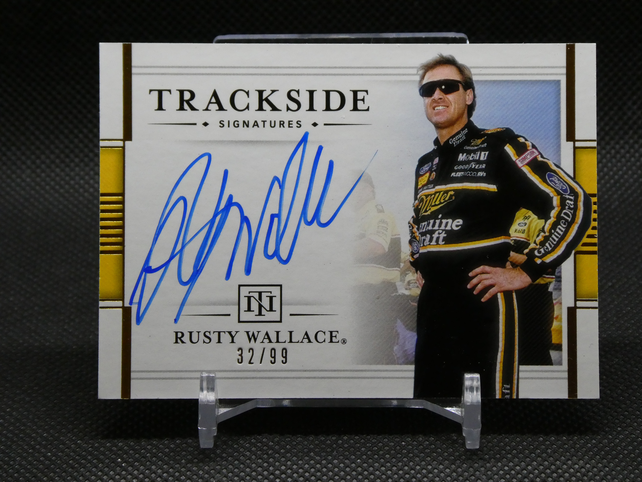 Autographed Rusty Wallace race card from Trackside Signatures, 32/99, with driver in racing suit on the right and blue signature in foreground.