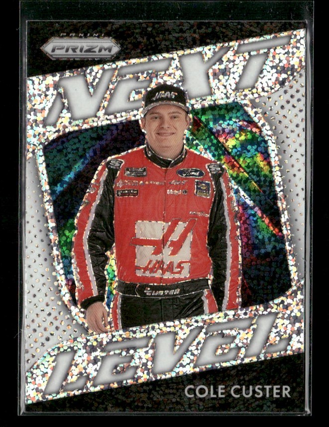 Trading card of NASCAR driver Cole Custer in a red racing suit with a holographic 'Reveal' design and bold borders.