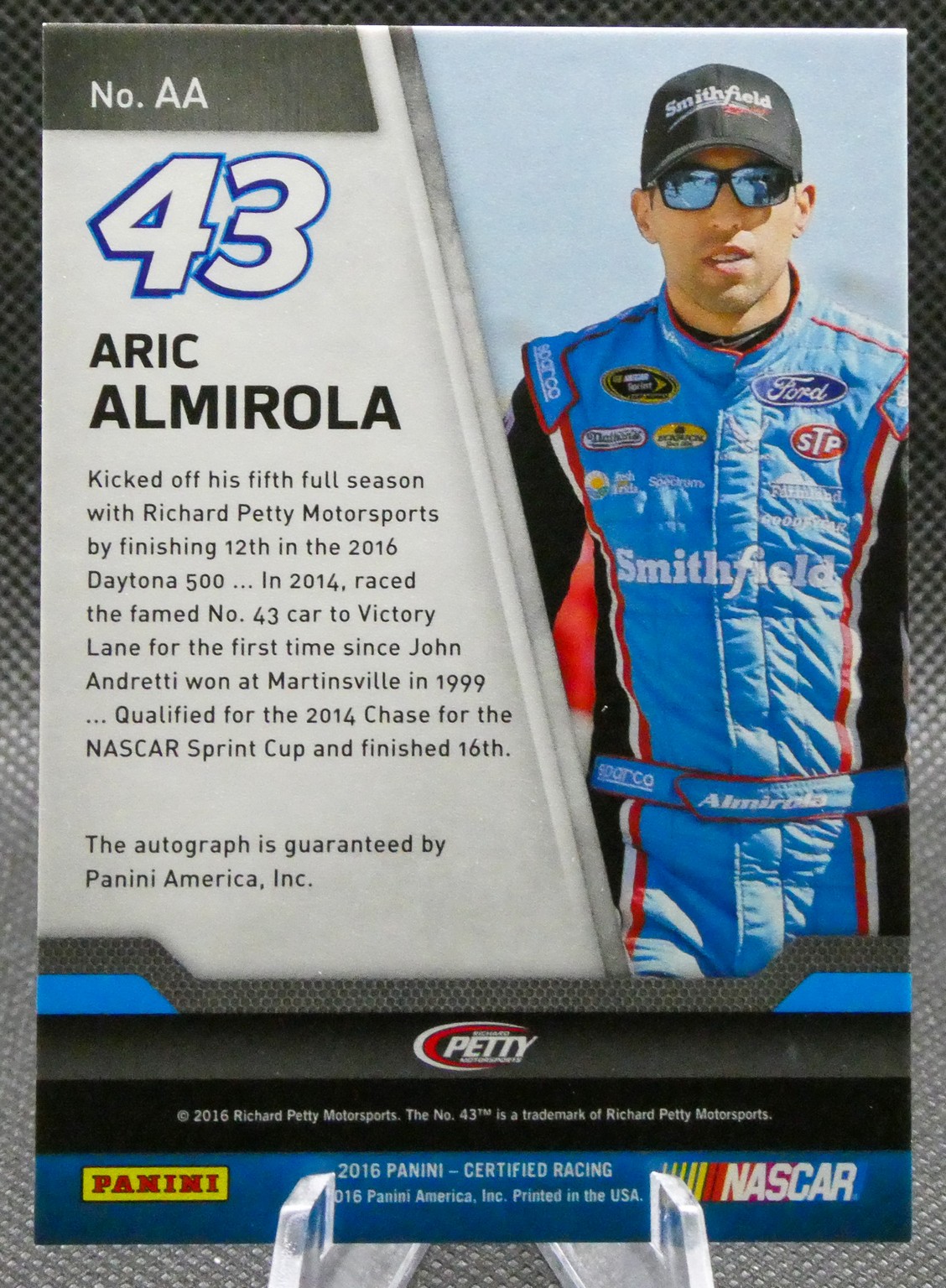 Trading card portrait of NASCAR driver Aric Almirola wearing a blue Smithfield racing suit, No. 43, with bio text on the left side.