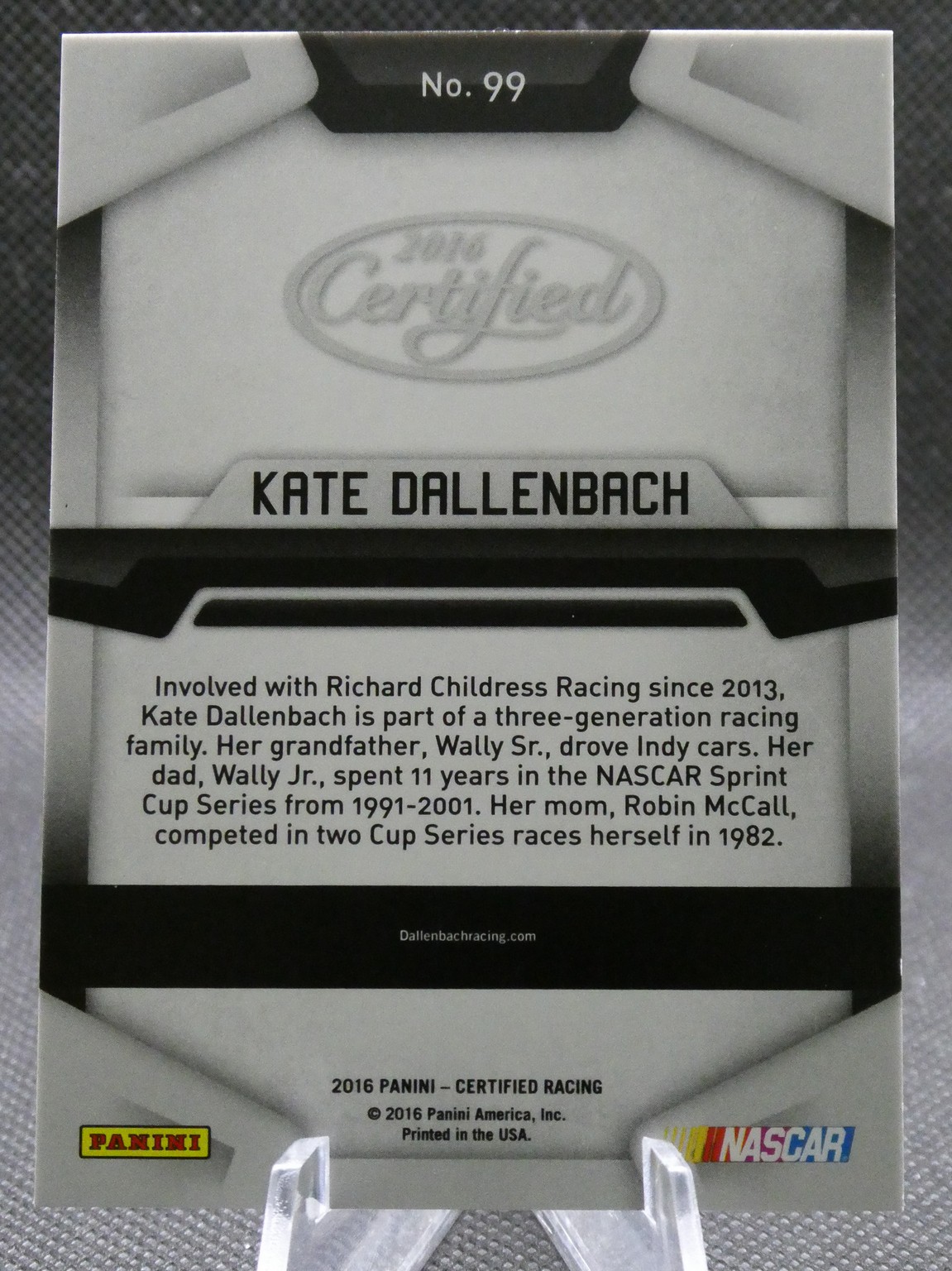 Close-up of a Kate Dallenbach trading card package showing No. 99 and a biographical paragraph about her racing background at the bottom edge of the card.