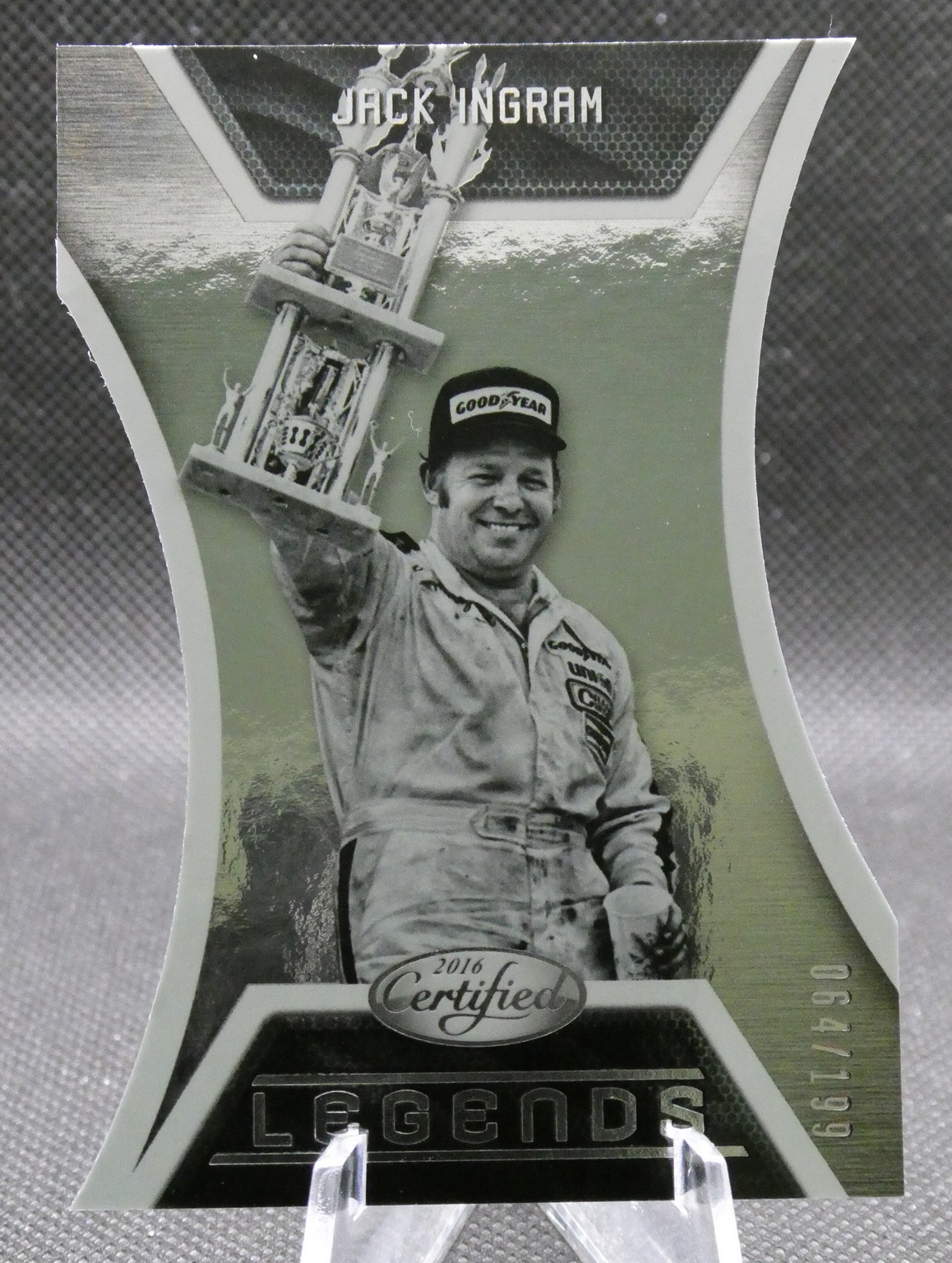 Black-and-white portrait of Jack Ingram celebrating with a large trophy, wearing a racing suit and a Goodyear cap, on a 'Legends' collectible card.