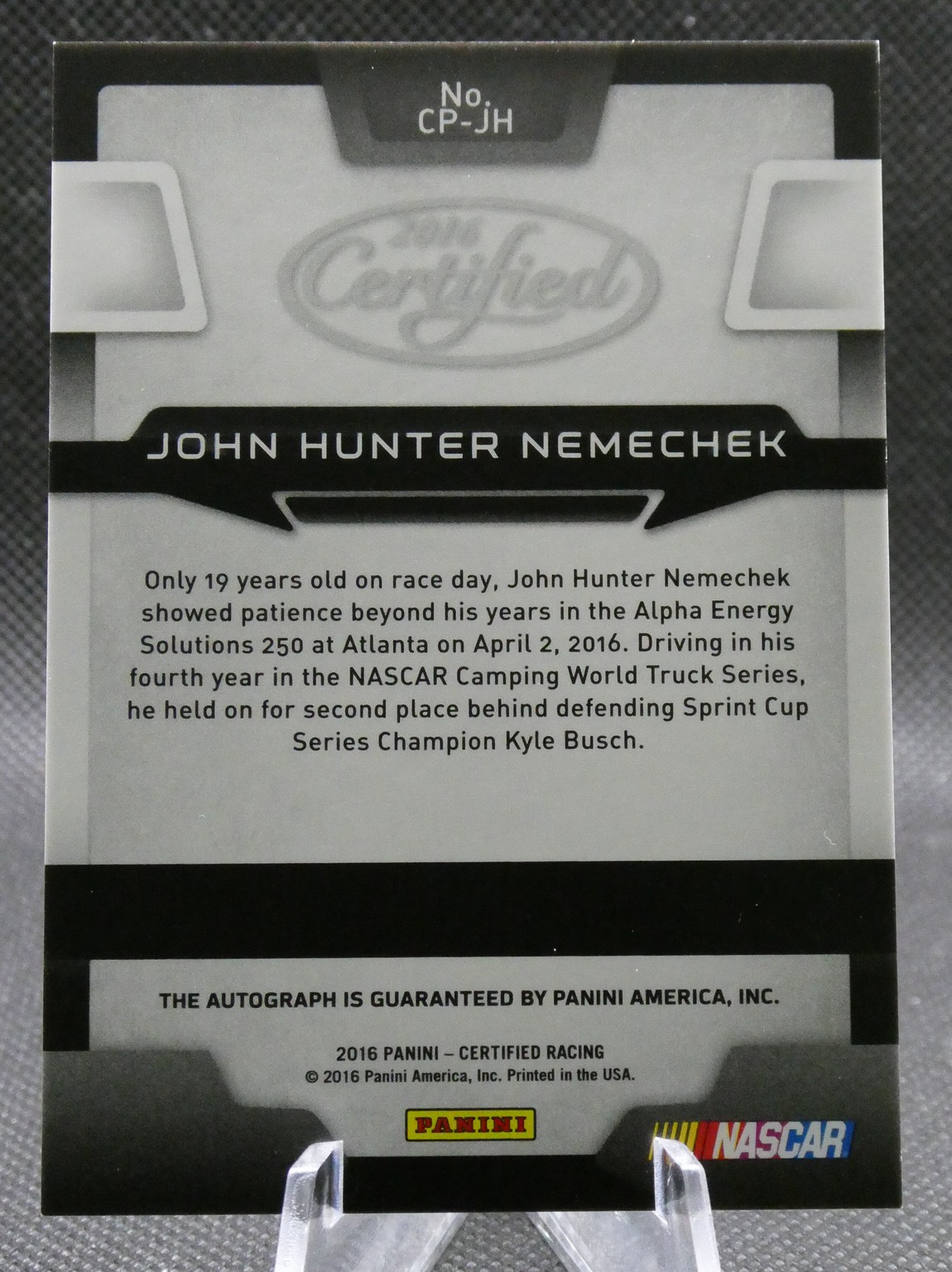 Back of a Panini NASCAR trading card for John Hunter Nemechek, showing his bio paragraph and logos partially visible at bottom.