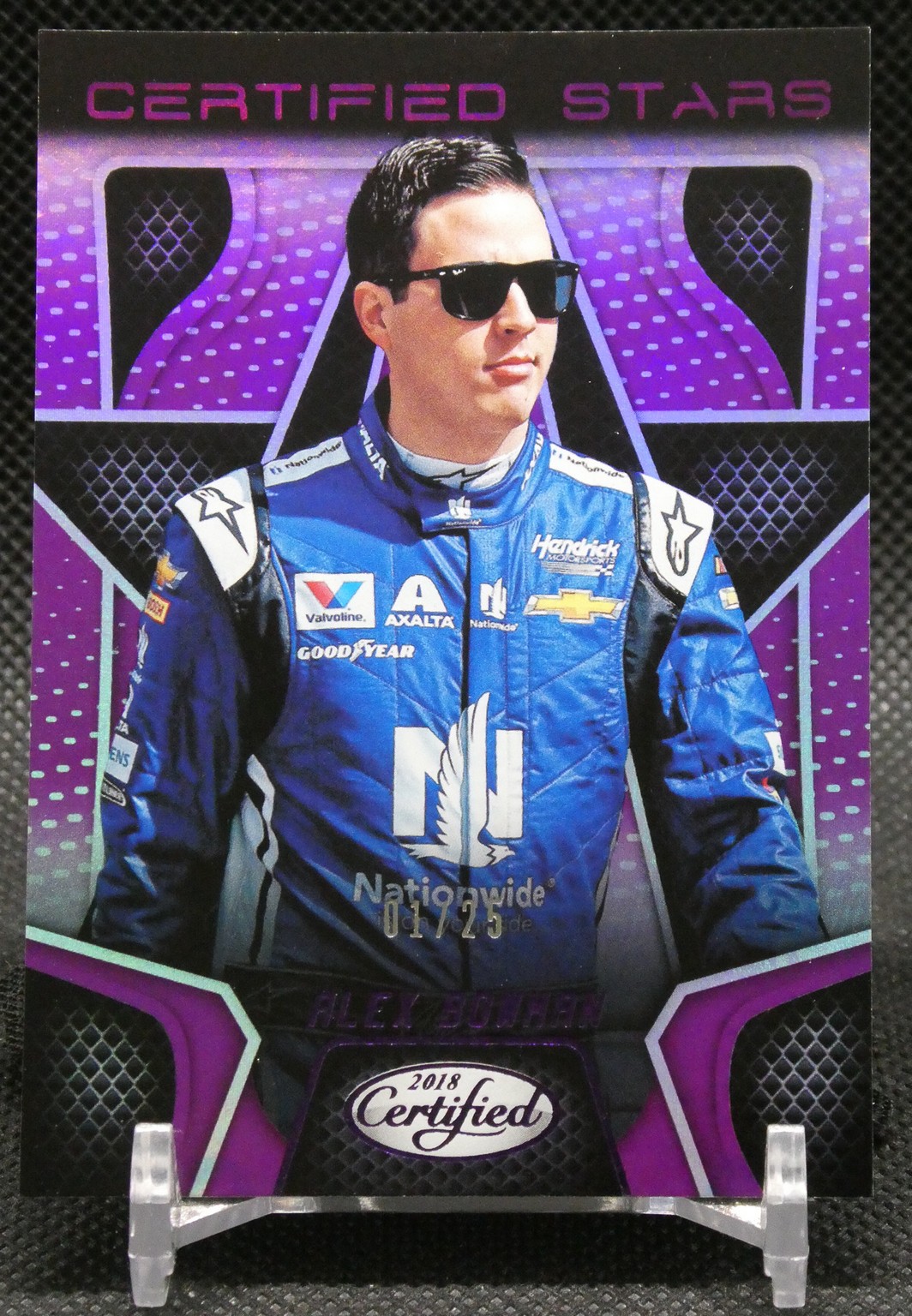 Portrait of a race car driver in a blue suit with sunglasses, in front of a purple 'Certified Stars' backdrop.