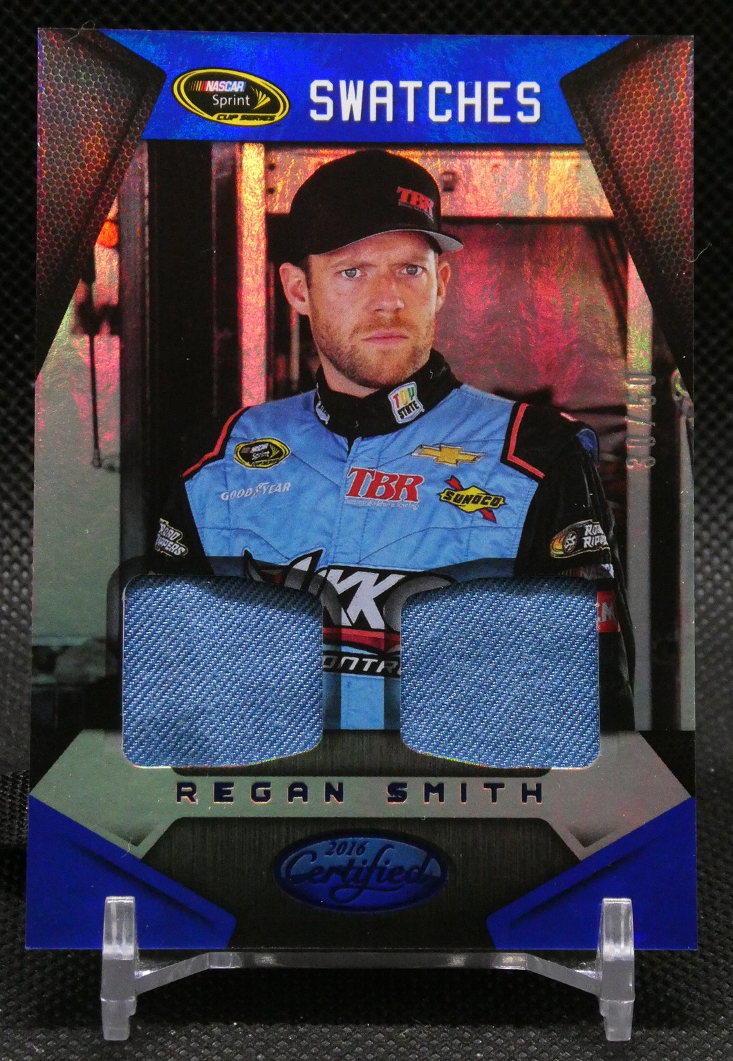 Trading card featuring NASCAR driver Regan Smith in a blue racing suit, with two fabric swatches and a 'Swatches' header at top.