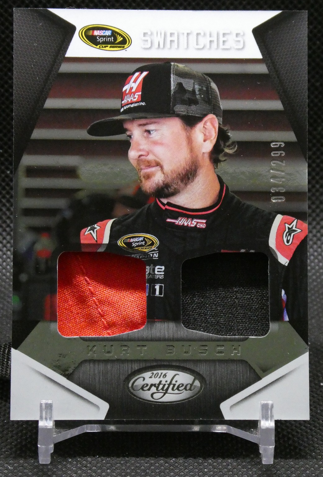 Kurt Busch NASCAR trading card with his portrait, showing two embedded fabric swatches (red and black) and 2016 Certified Swatches branding.