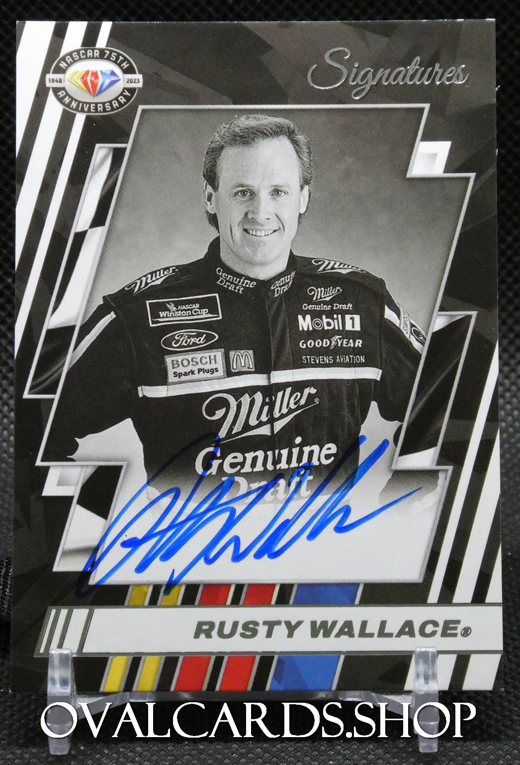 Black-and-white autographed NASCAR trading card featuring Rusty Wallace in his sponsor racing suit with a blue ink signature across the photo.