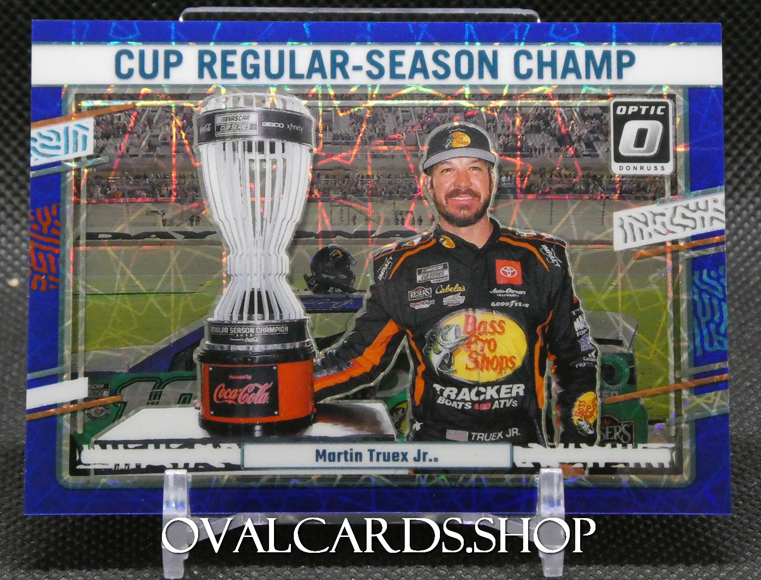 Trading card of Martin Truex Jr. posing with the Cup Regular-Season Champion trophy in a racing suit.