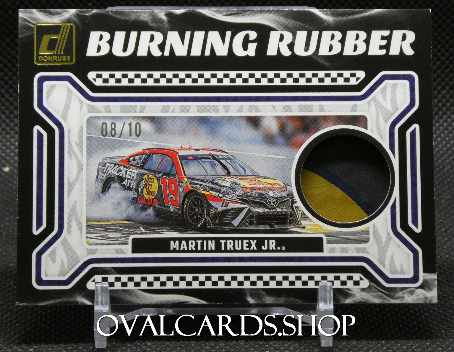 Trading card titled Burning Rubber featuring Martin Truex Jr.'s #19 NASCAR truck; includes a circular cutout with a yellow-gold emblem and a photo of the racecar on a track.