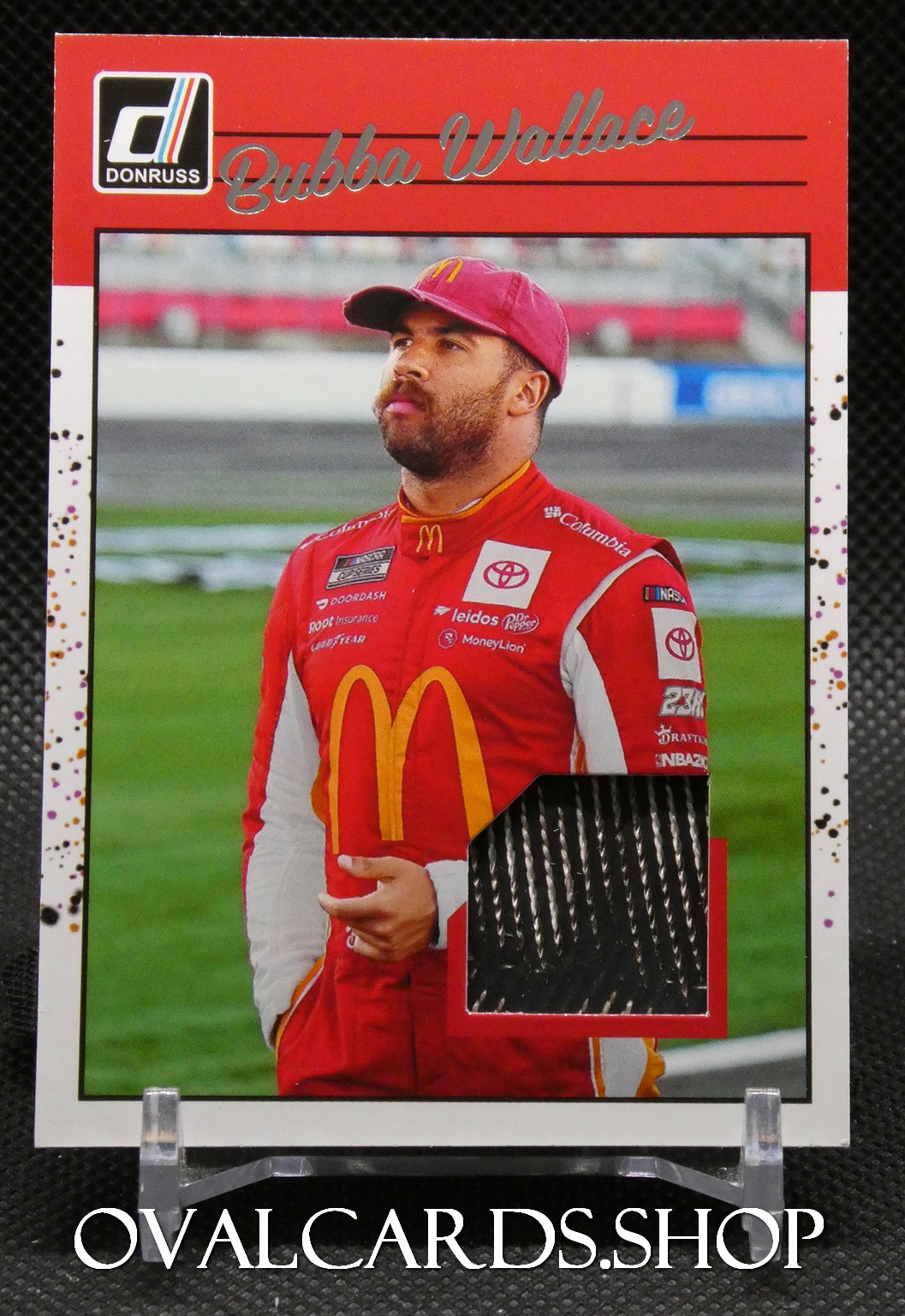 Trading card portrait of NASCAR driver Bubba Wallace in a red McDonald's racing suit, Donruss logo and Bubba Wallace name at top, with a black fabric swatch inset on the lower right.