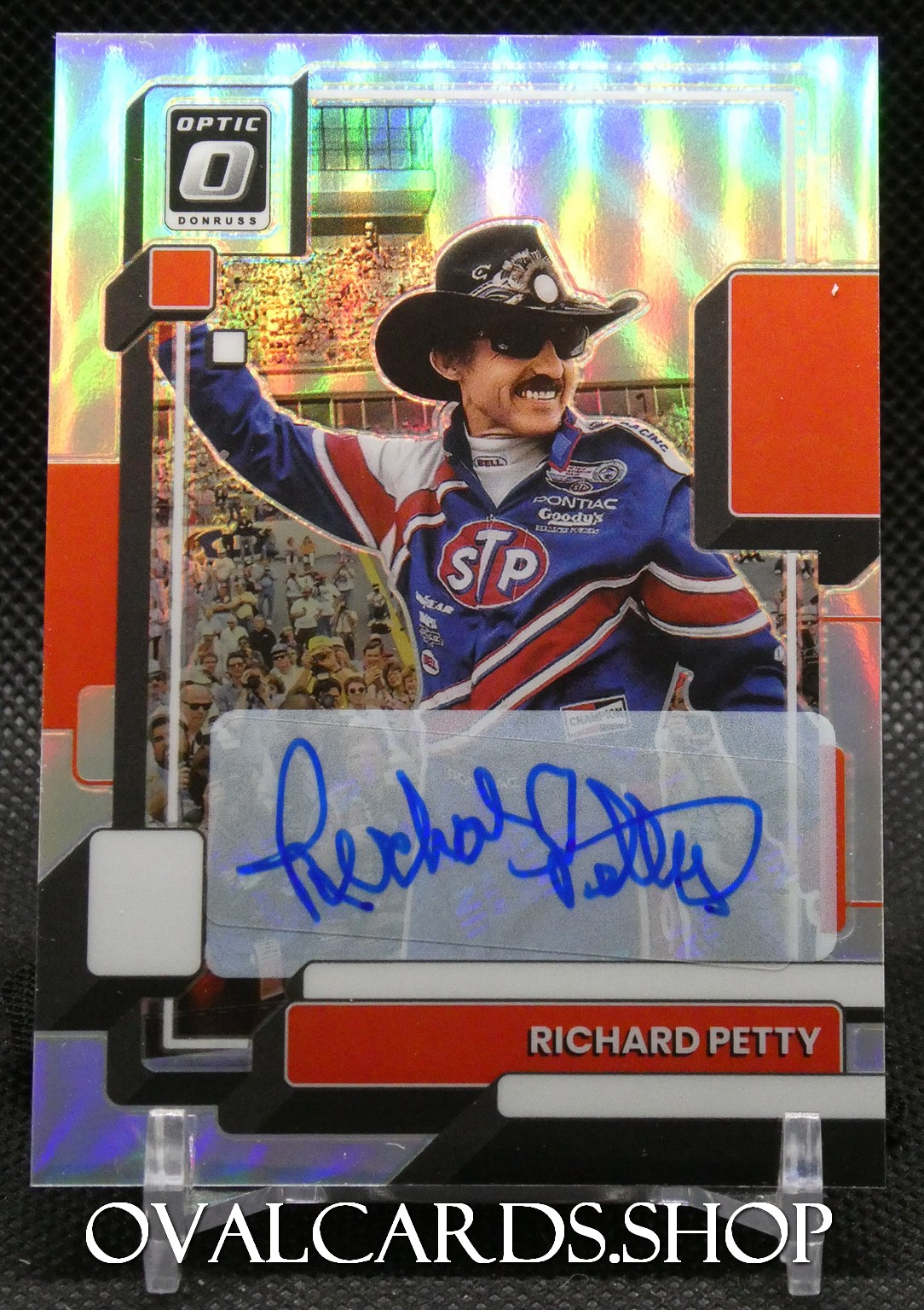 Autographed racing trading card featuring a driver in a blue STP Goody’s racing suit, wearing a black cowboy hat and sunglasses, with a holographic background and a blue signature across a white sticker area.