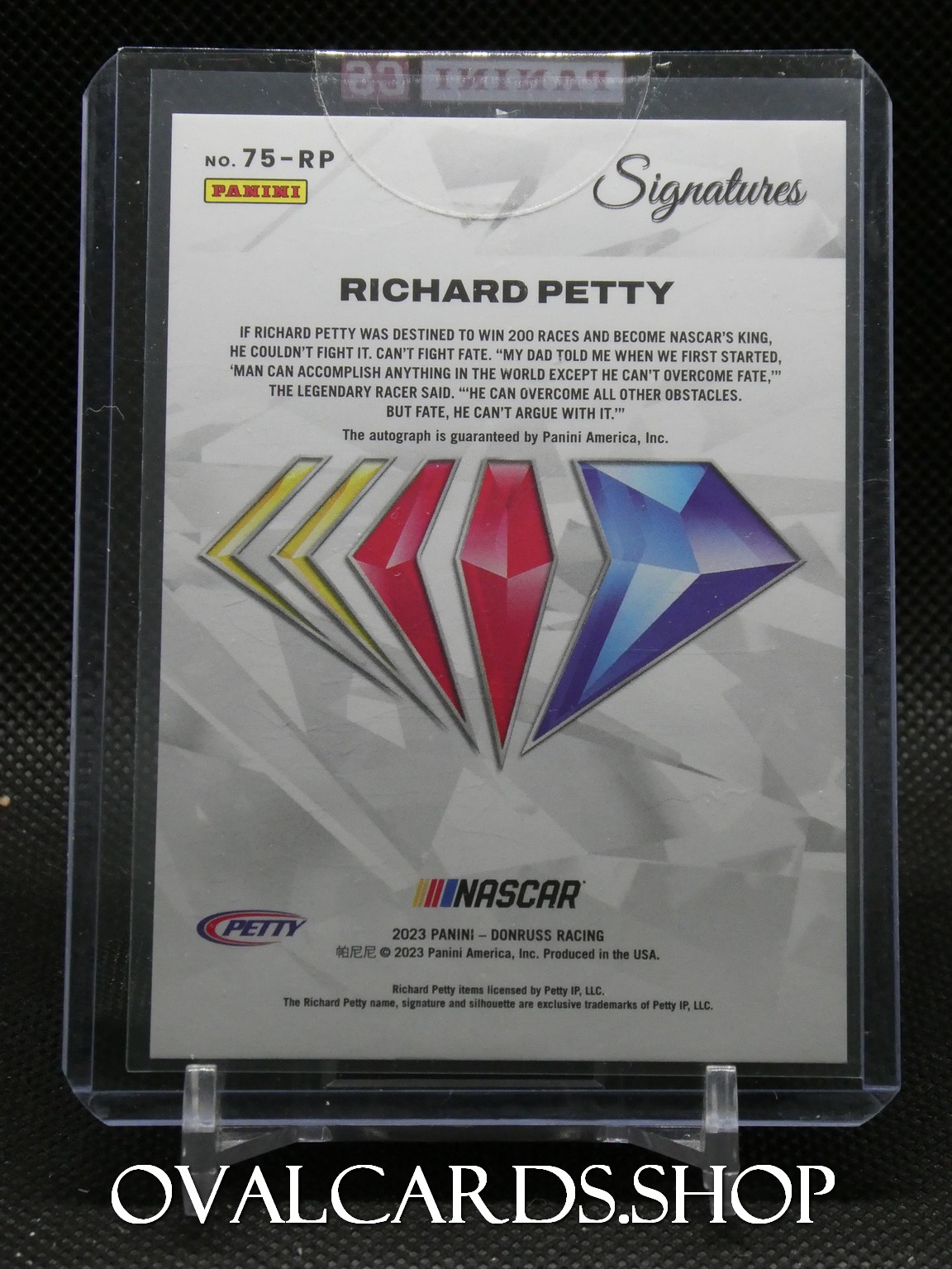 Panini Signatures Richard Petty autographed card in clear display case with diamond graphics and NASCAR logo on bottom edge (text-heavy back).