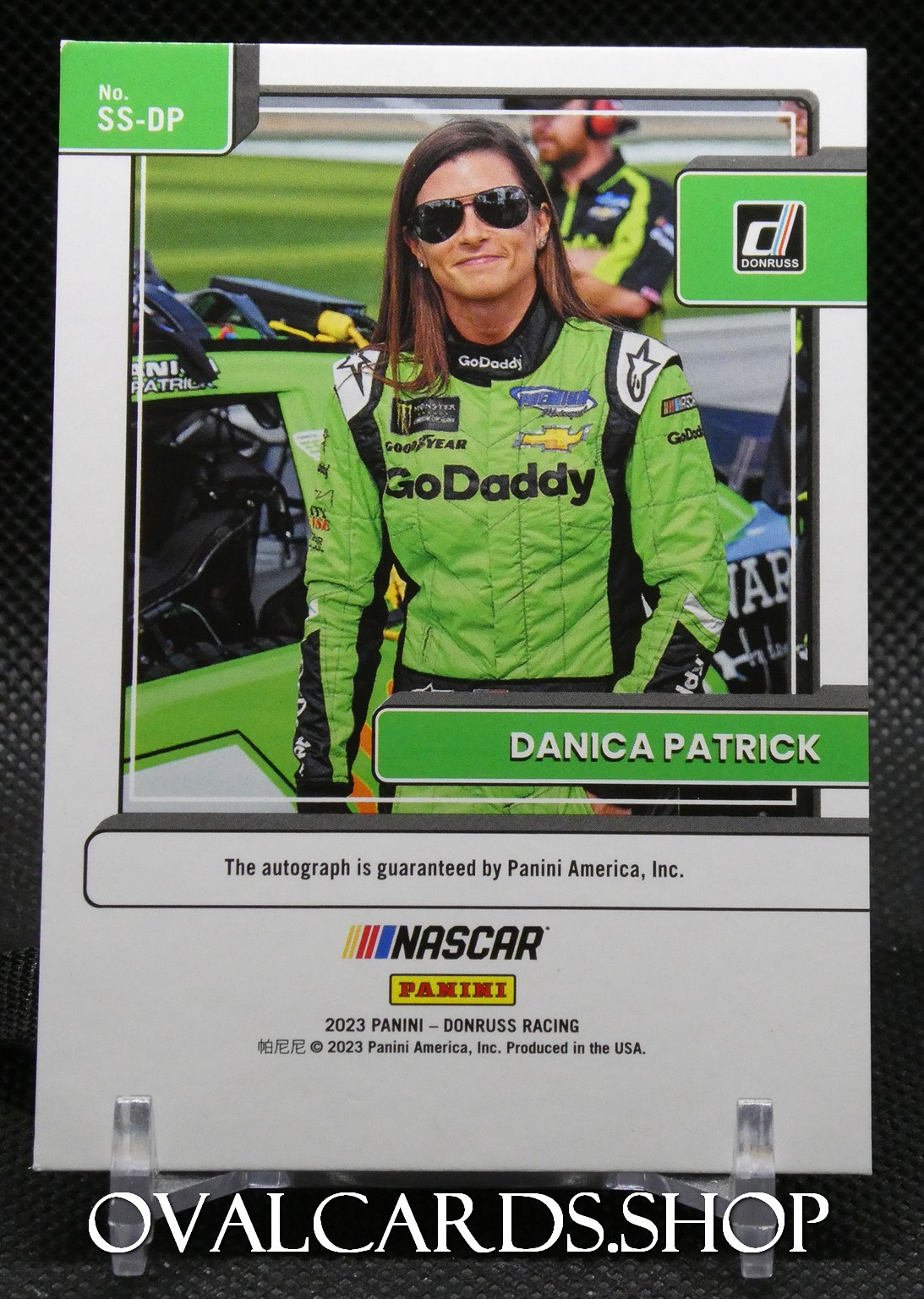 Trading card featuring Danica Patrick in a green GoDaddy racing suit beside a race car.