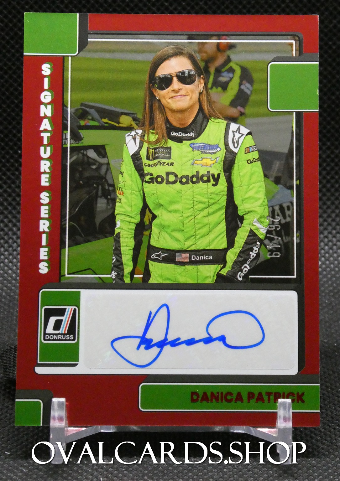 Trading card of Danica Patrick in a bright green GoDaddy racing suit with her signature area at the bottom.