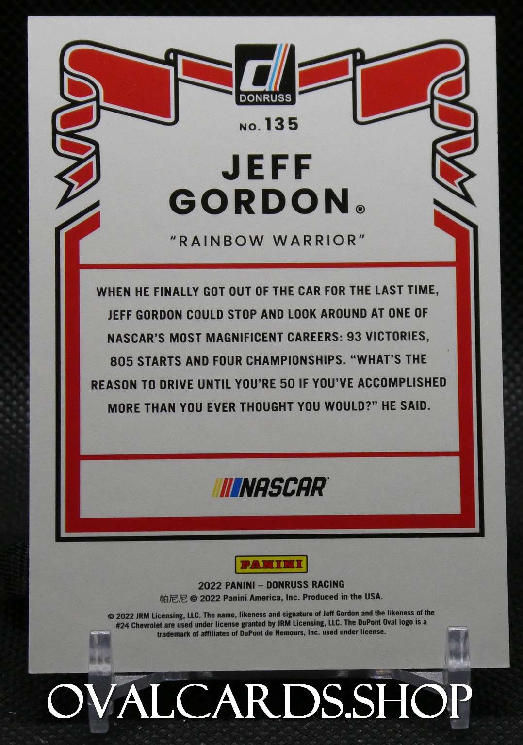 Back of a Panini NASCAR trading card for Jeff Gordon, titled 'Rainbow Warrior,' with red borders and logos (NASCAR, Panini).